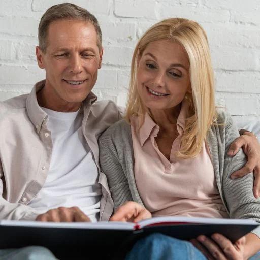 smiling-couple-looking-at-notebook-while-sitting